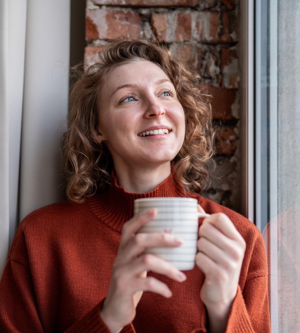 Content woman gazing upwards holding cup of coffee